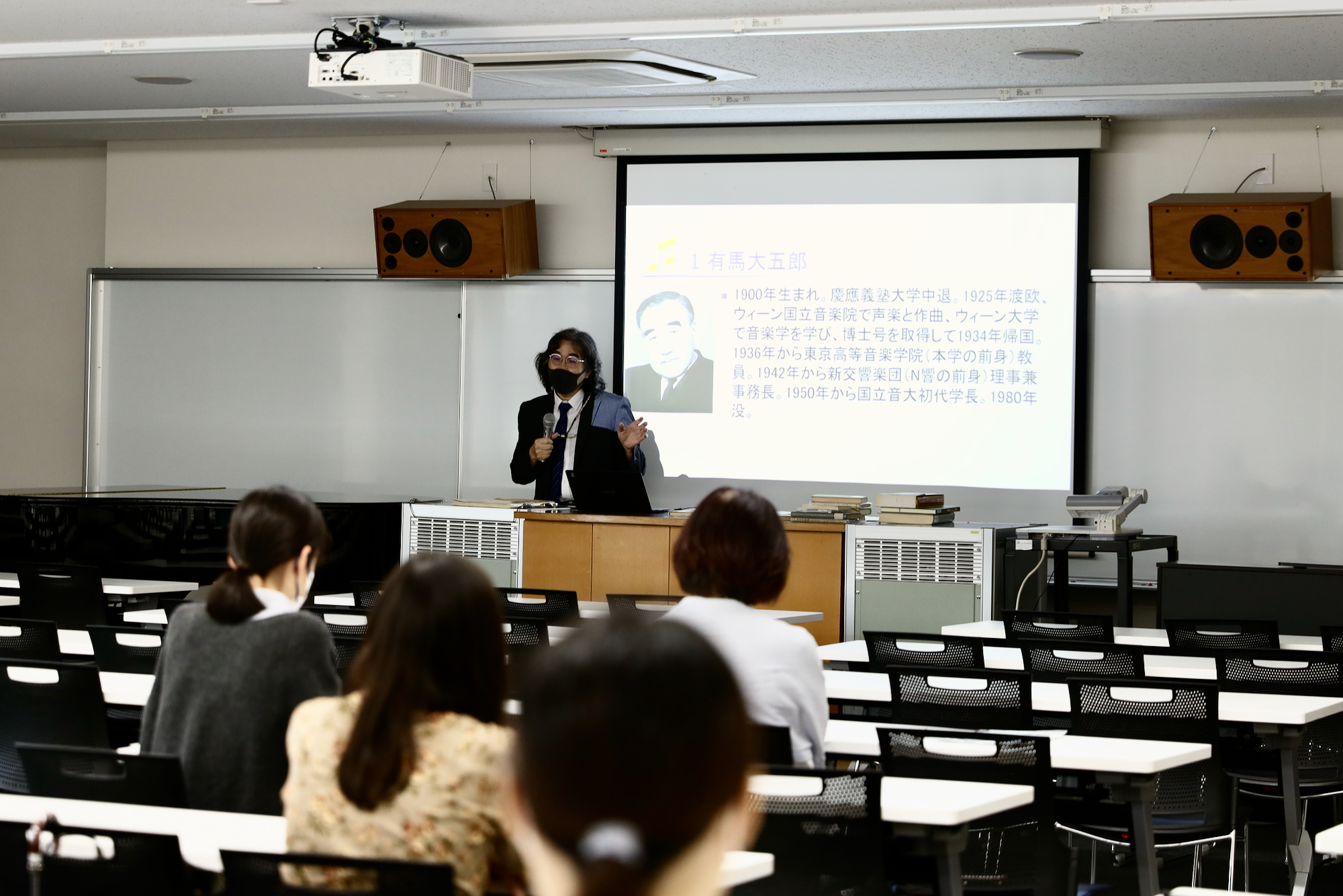 本学初代学長の有馬大五郎先生についてお話しされている吉成先生の写真